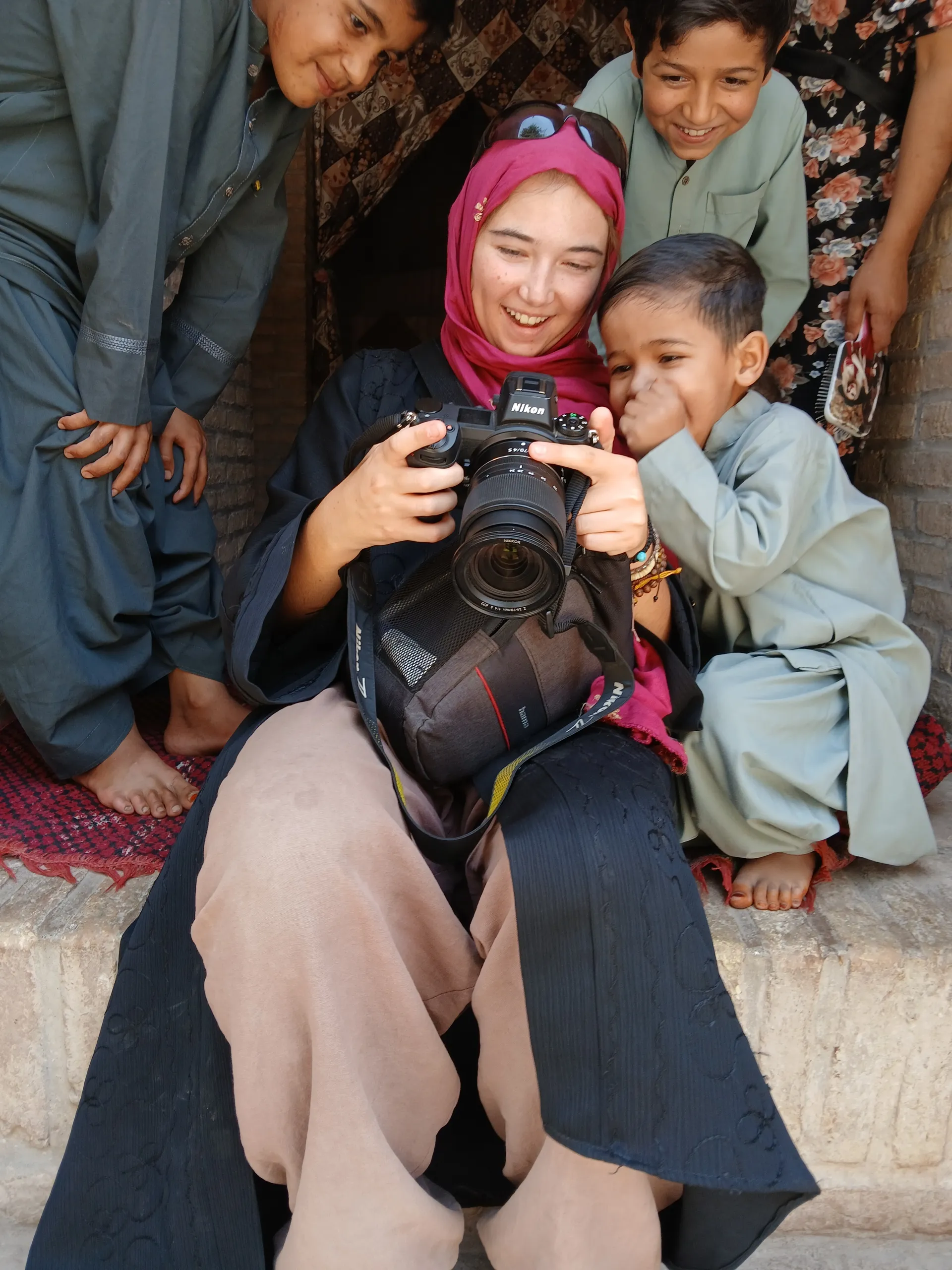 Showing her travel photos to curious kids in Herat