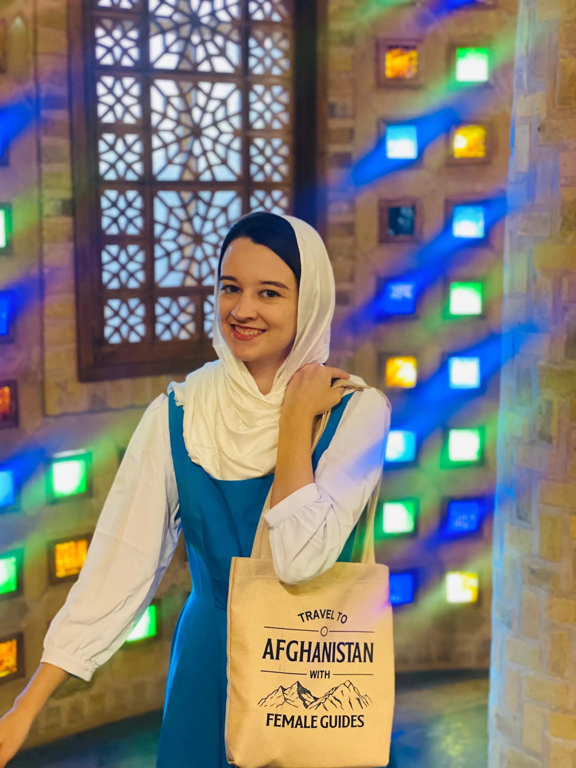 Wearing a gift from Afghanistan female tour guides during her journey, standing in a traditional restaurant in Herat